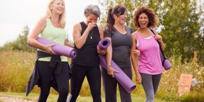 Group Of Mature Female Friends On Outdoor Yoga Retreat Walking Along Path Through Campsite